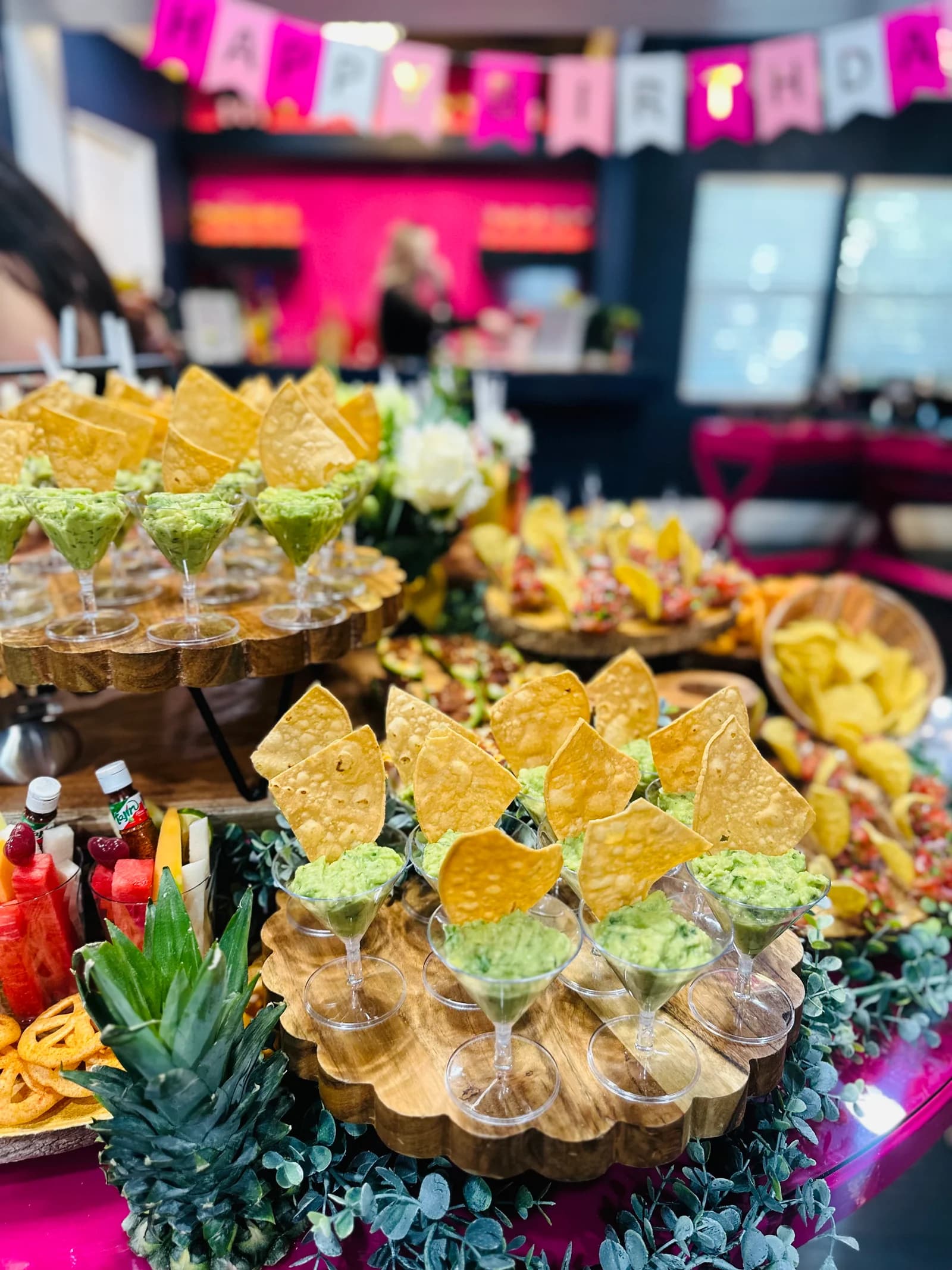 Fiesta table with individual guacamole cups, tortilla chips, fruit, and savory bites