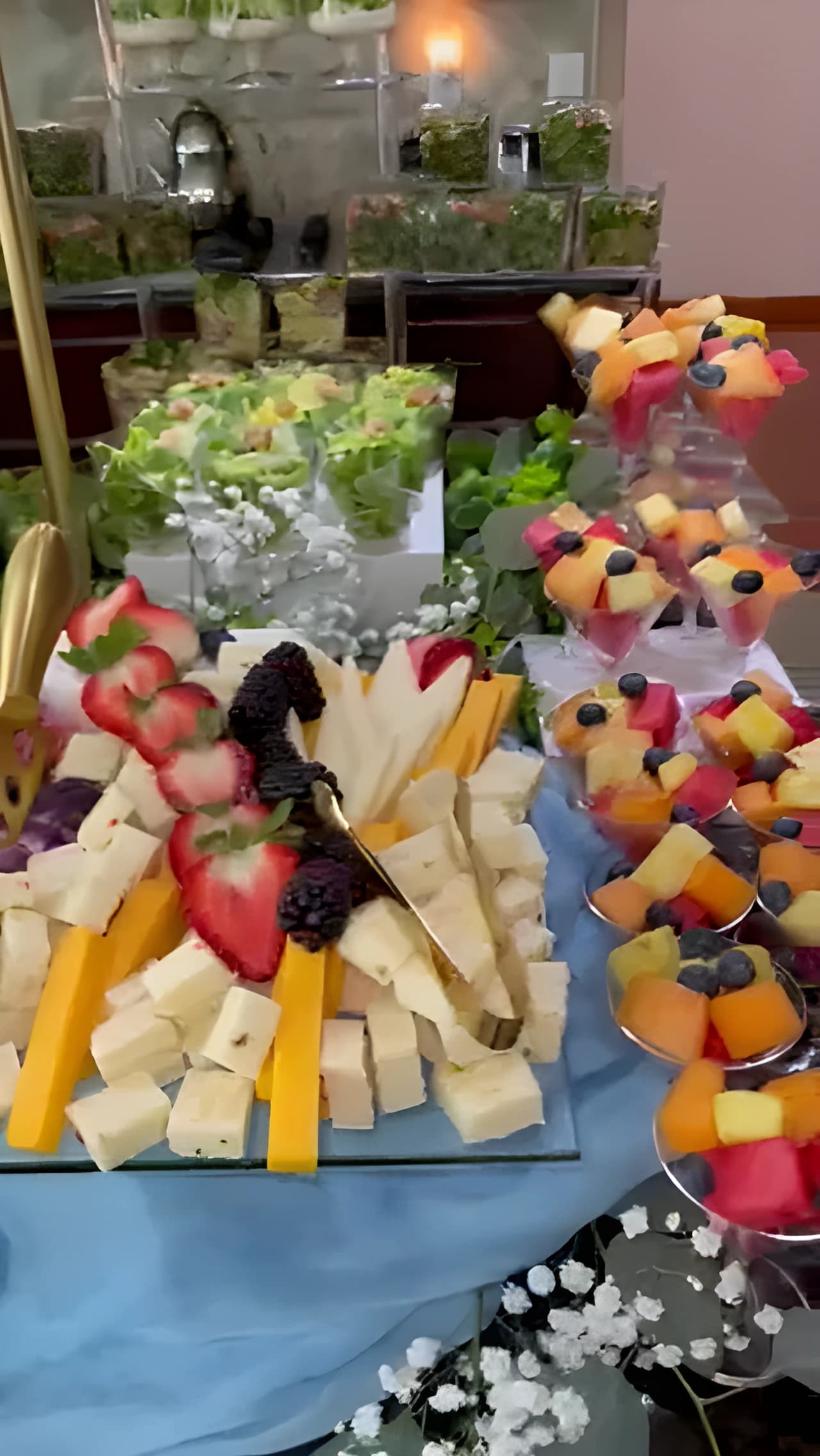 Blue grazing table with cheeses, berries, crackers, and individual fruit cups