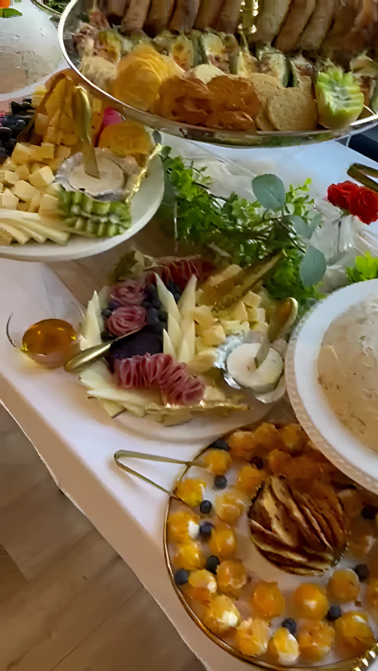 White grazing table with sandwiches, stuffed grape leaves, appetizer cups, and serving trays