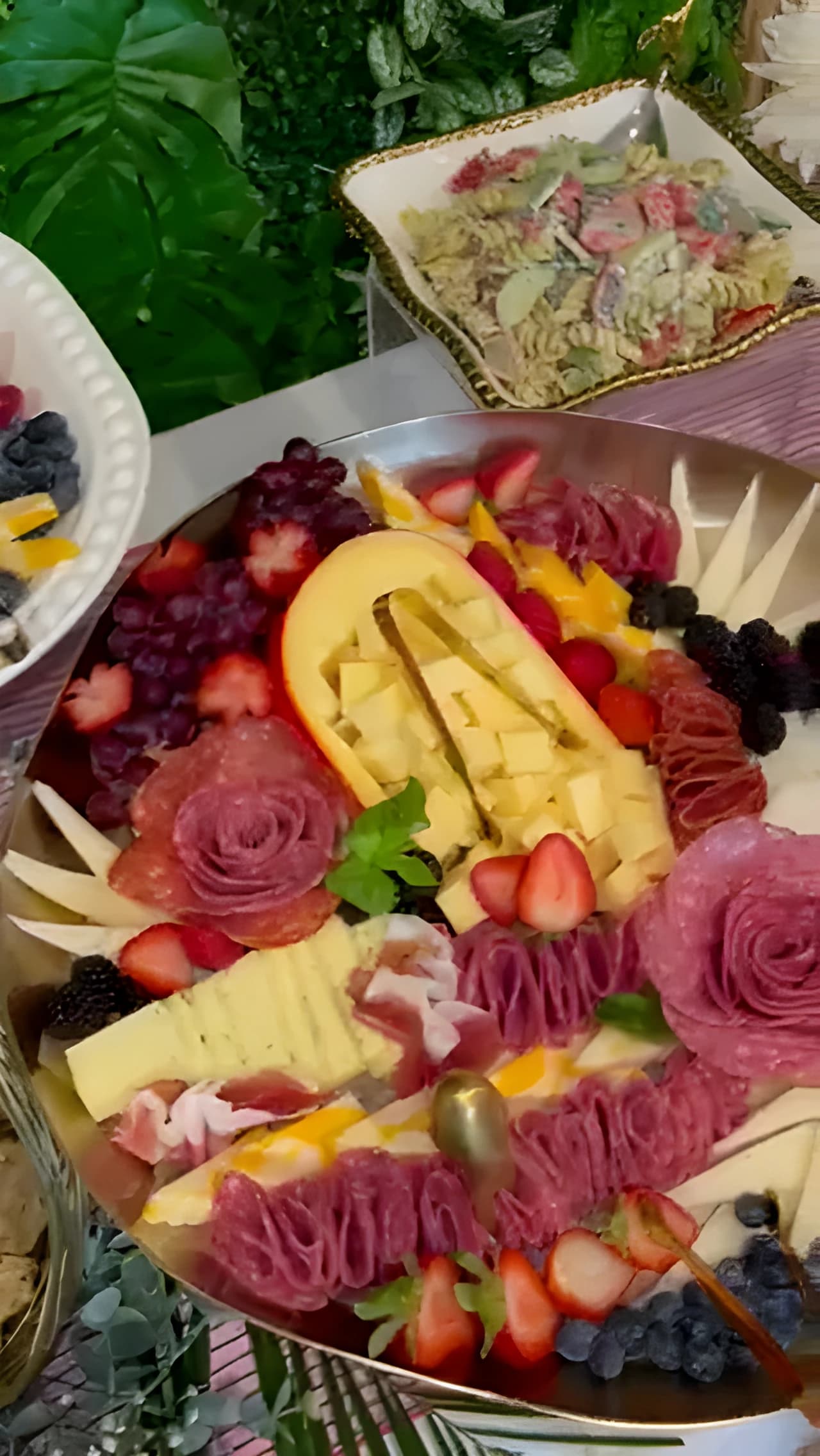 Charcuterie board with folded meats, cheeses, strawberries, blackberries, and crackers
