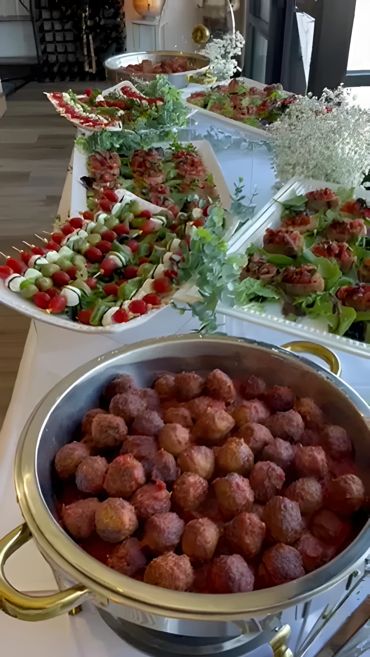 Meatball chafing dish in front of Caprese skewers and bruschetta trays