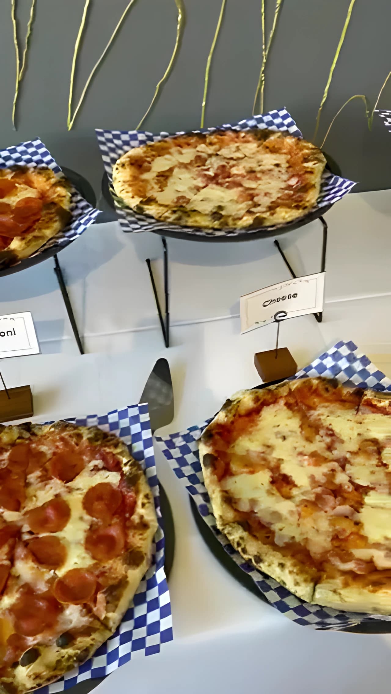 Pizza table with labeled pies on raised black stands