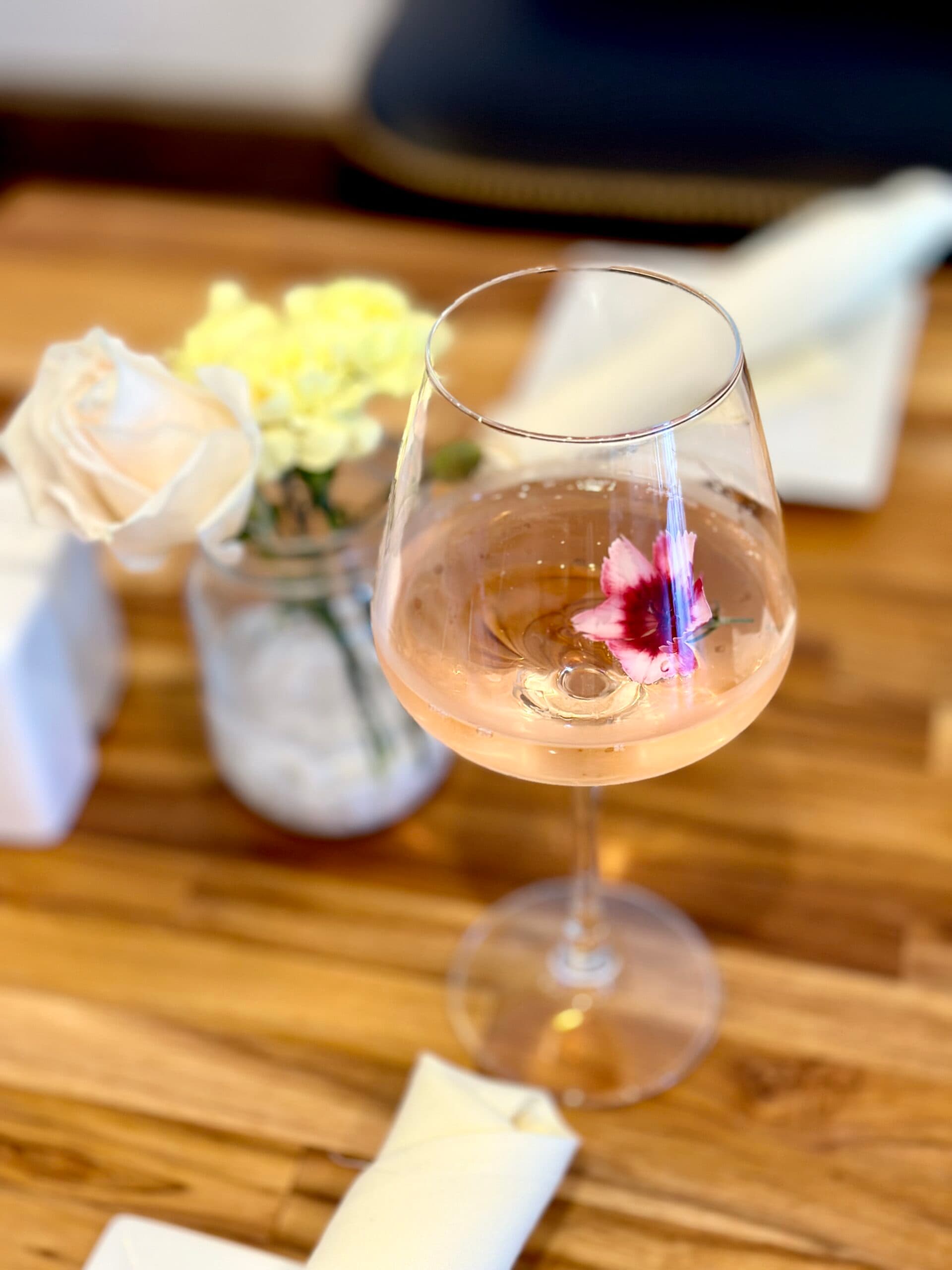 Rose wine glass and floral detail on a warm wood table