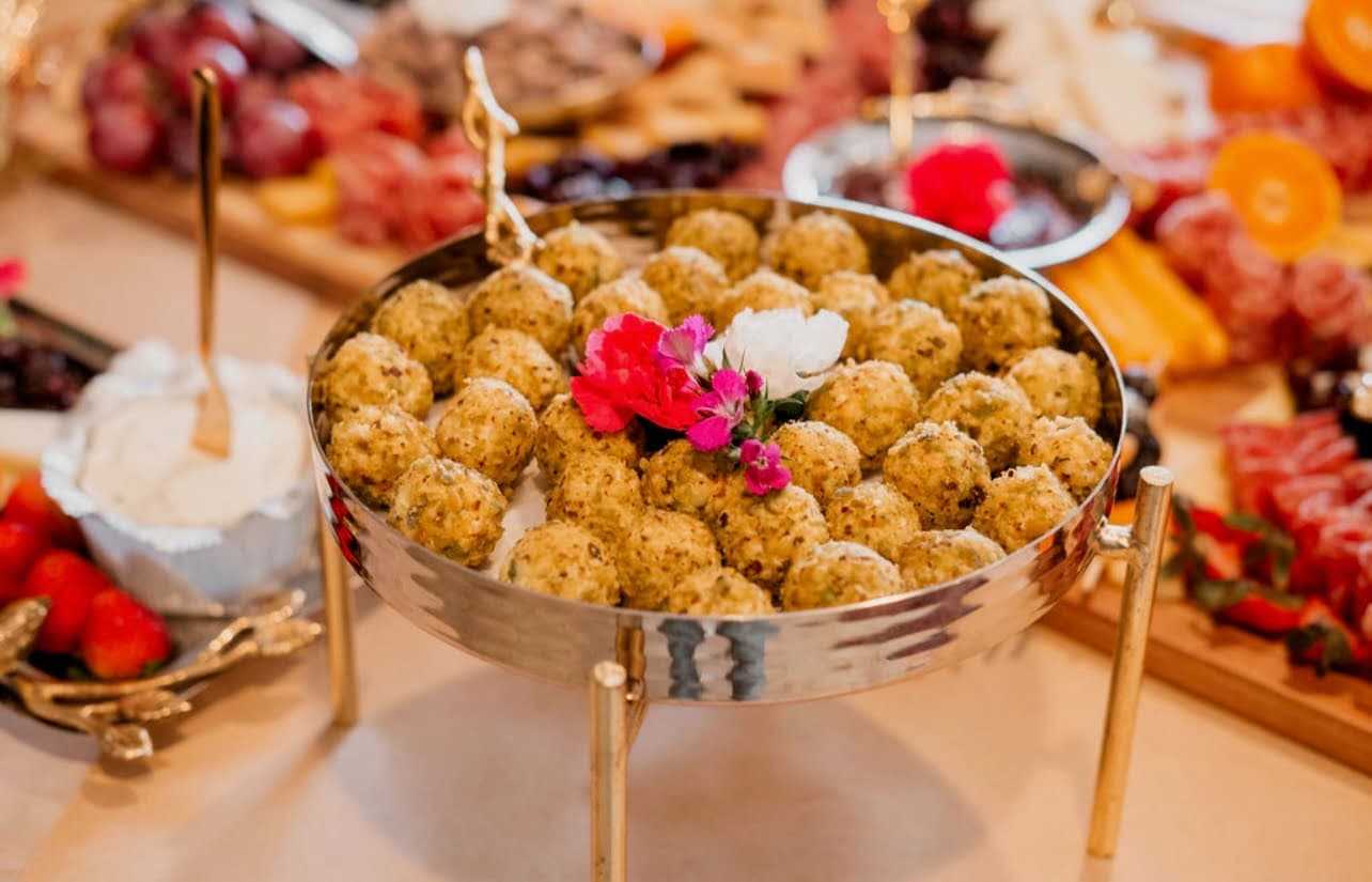 Gold stand filled with herbed meatballs on an event table