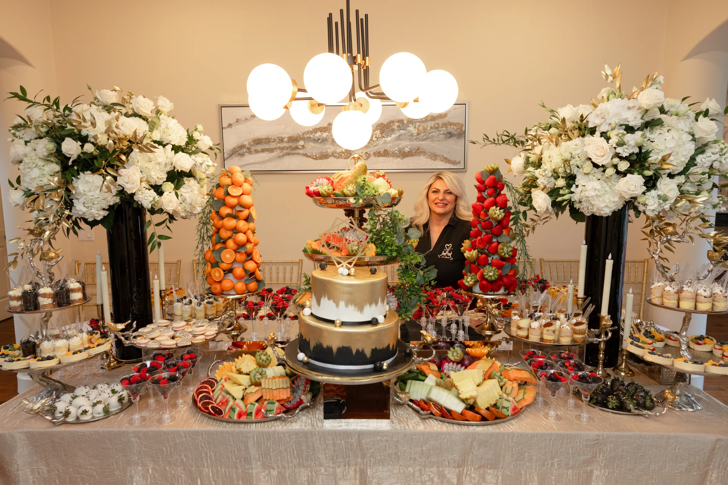 Ilona standing behind a full L’Amore fruit, sweets, and celebration display