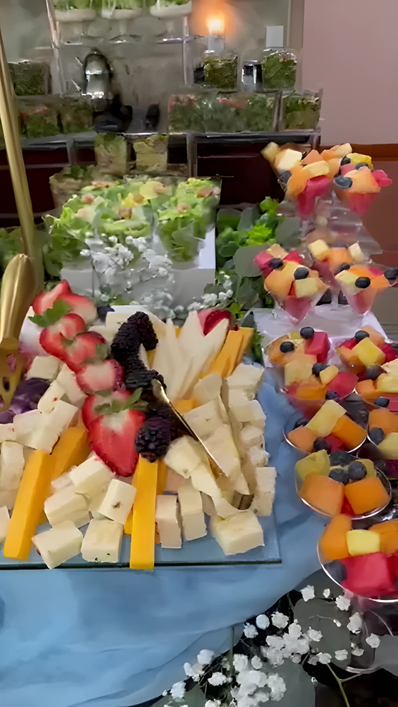 Blue grazing table with cheeses, berries, crackers, and individual fruit cups
