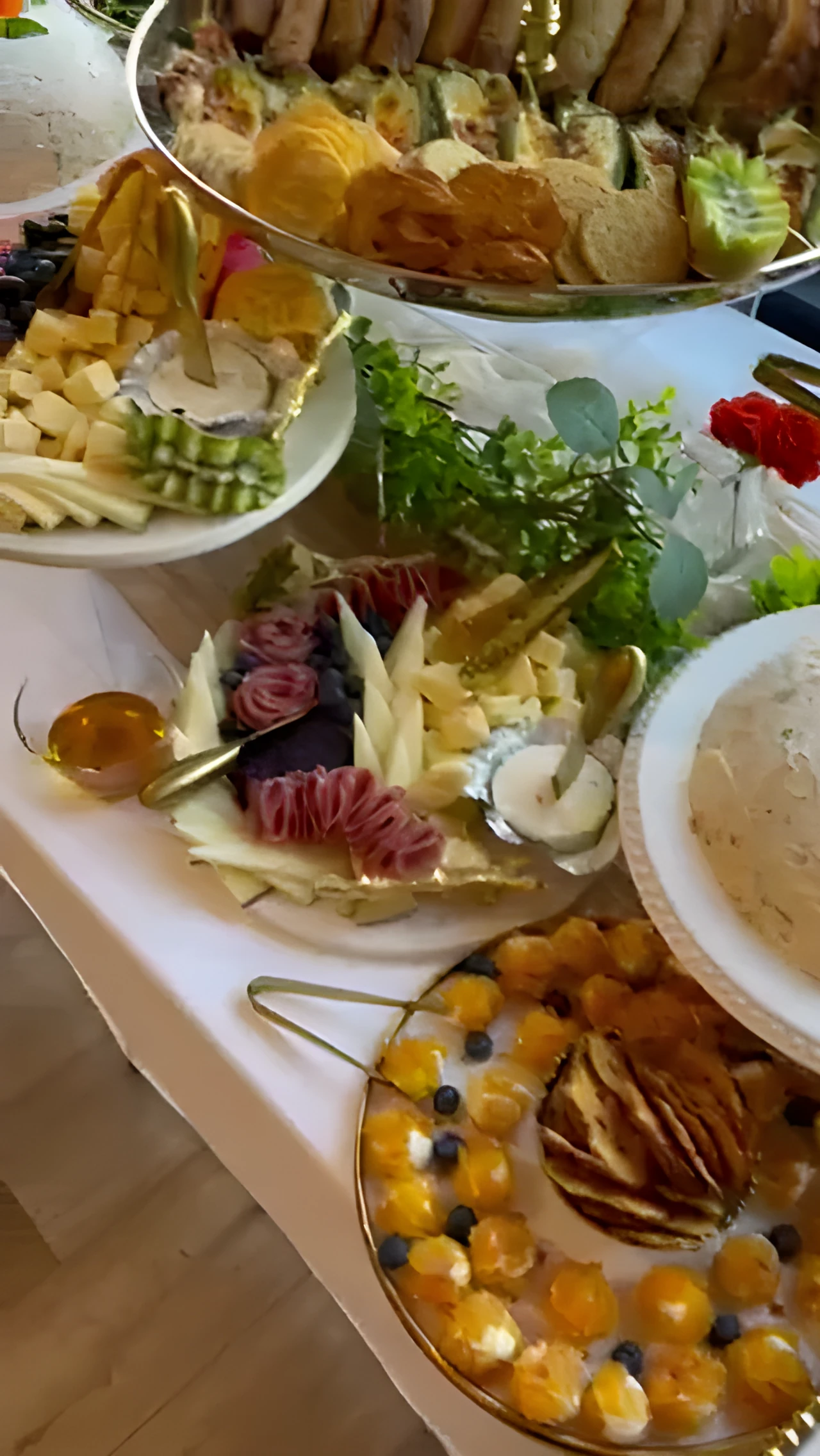 White grazing table with sandwiches, stuffed grape leaves, appetizer cups, and serving trays