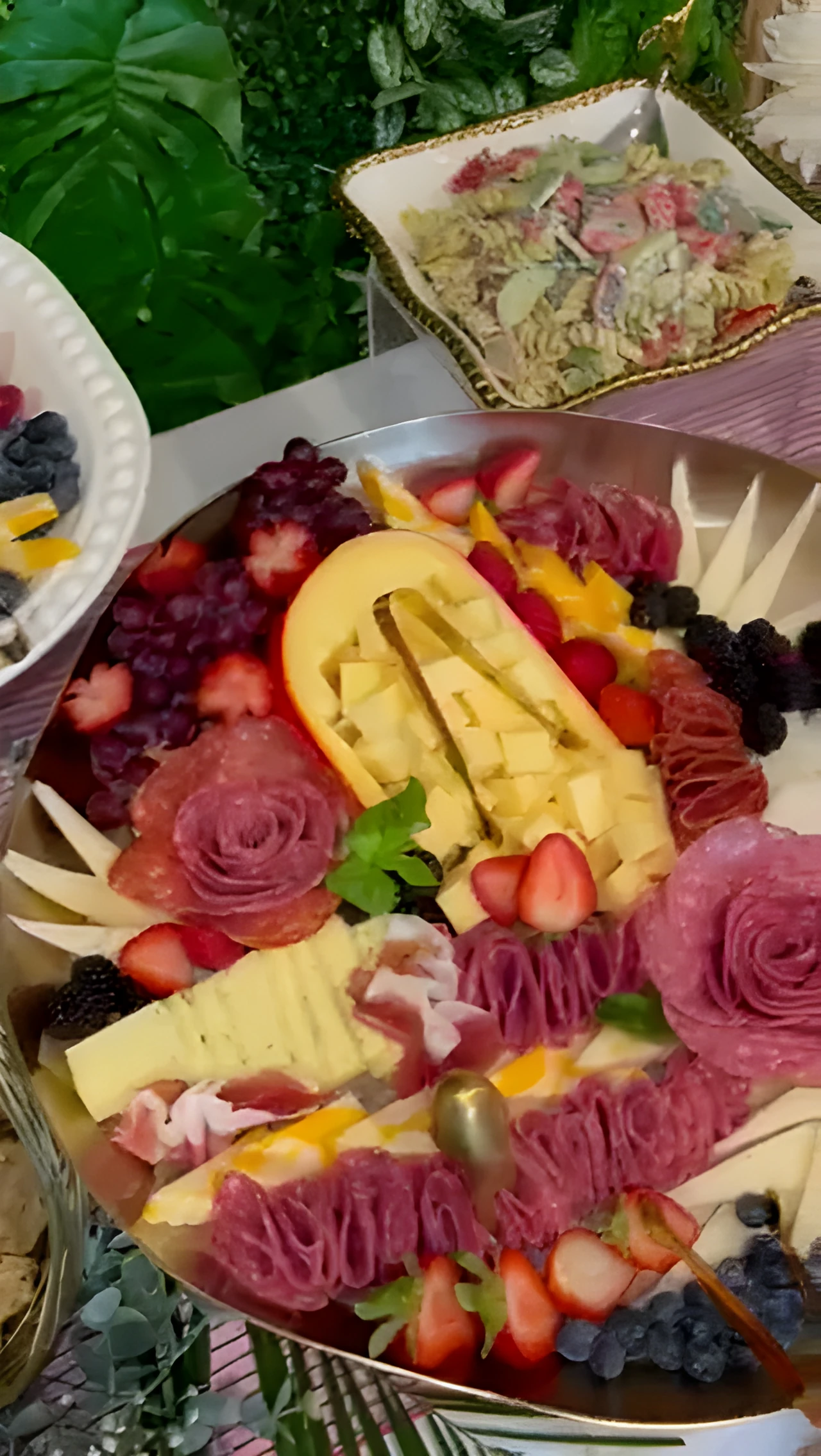 Charcuterie board with folded meats, cheeses, strawberries, blackberries, and crackers